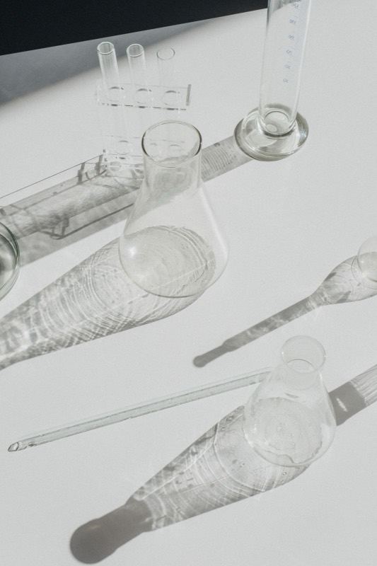 Clear lab glassware casting long shadows on a white surface