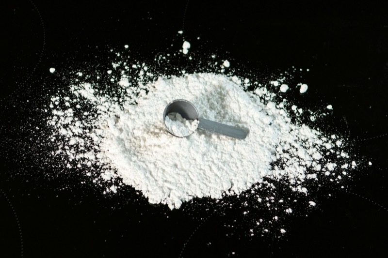 Small scoop in a pile of white powder on a black surface
