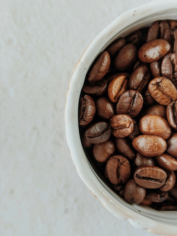 Roasted coffee beans in a white ceramic bowl, seen from above