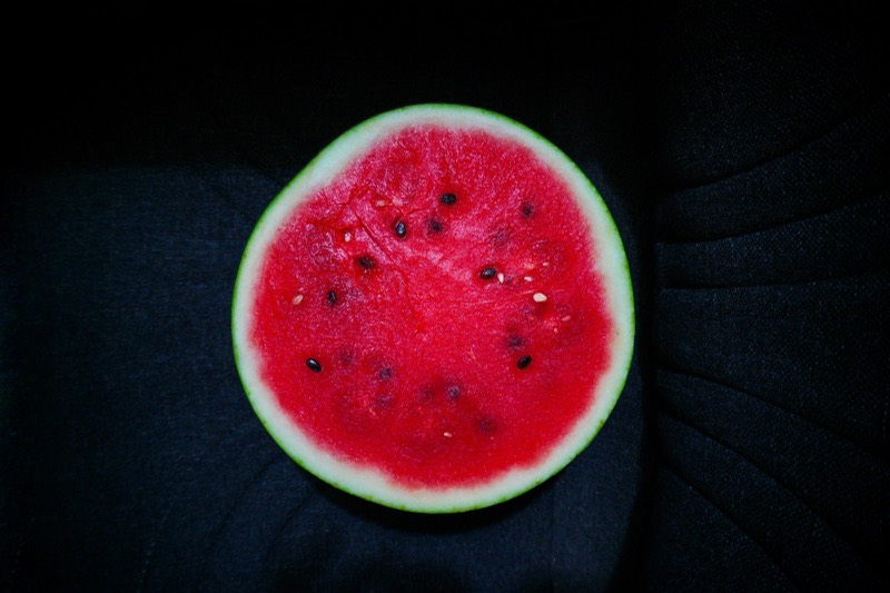Half a watermelon, cut face up, on dark fabric