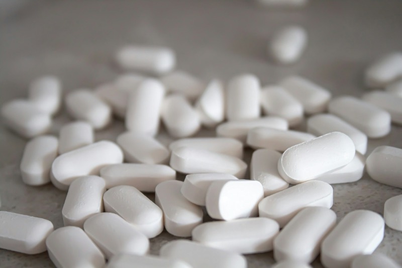 Scattered white oblong tablets on a grey surface