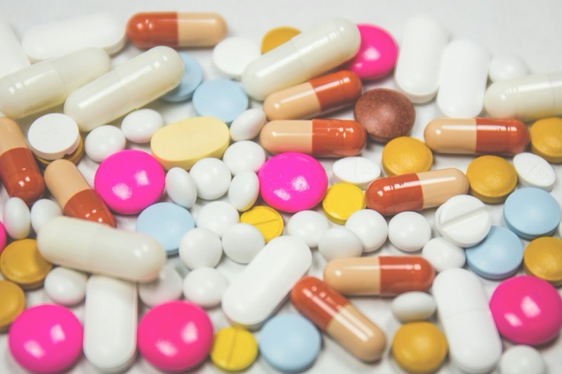 Assorted coloured tablets and capsules filling the frame